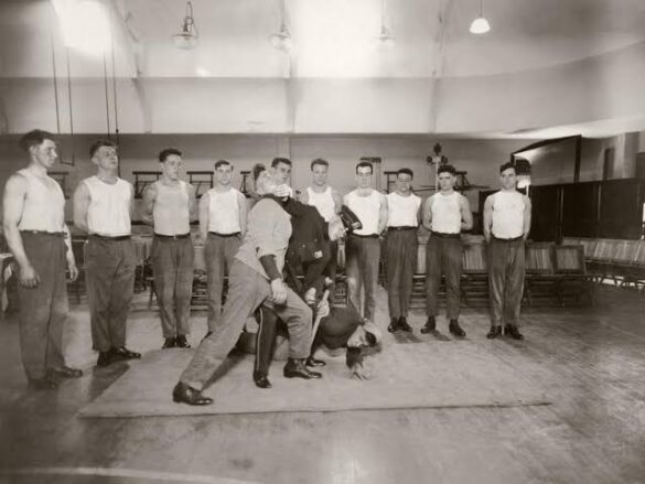 Foto antiga de instrução de defesa pessoal para uma turma de homens enfileirados